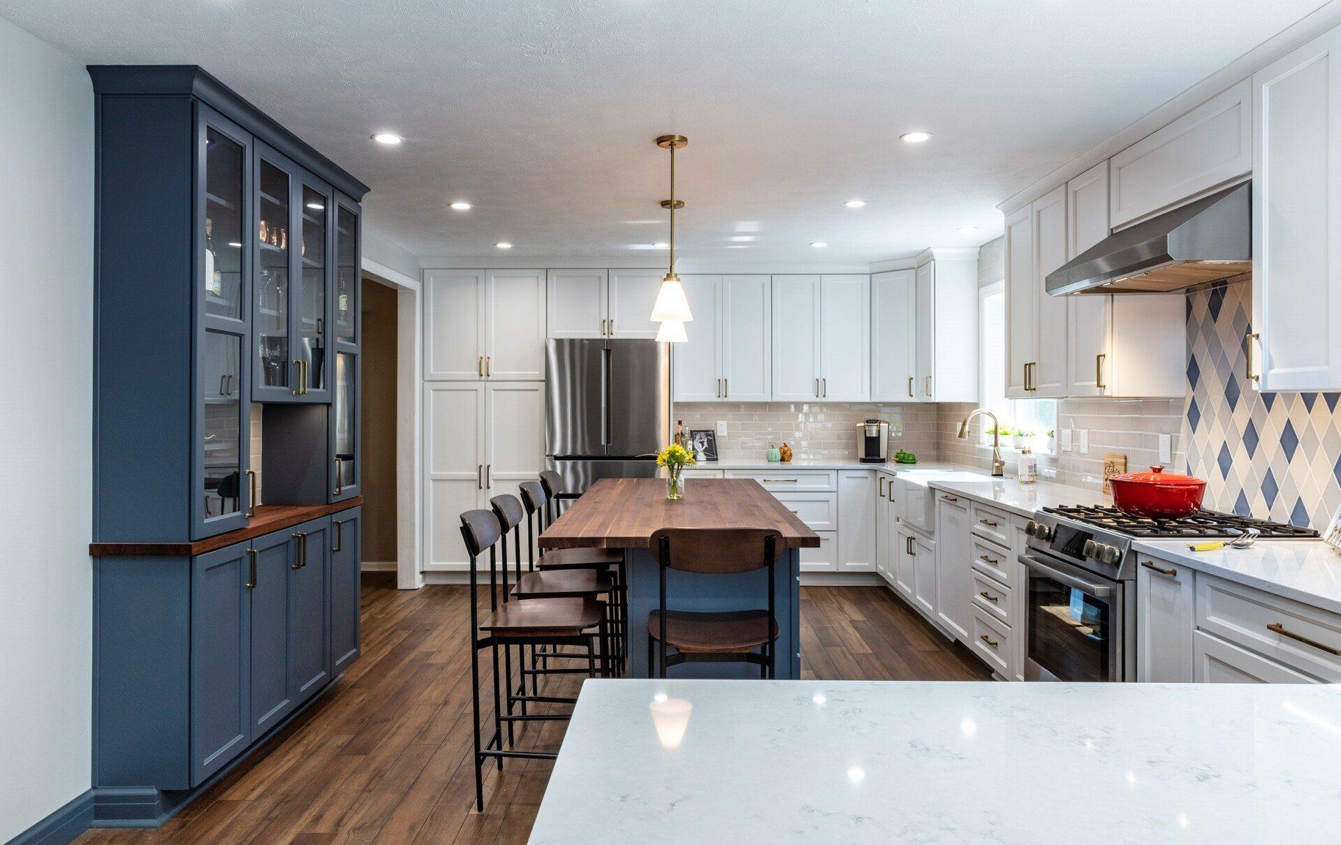 Modern kitchen with blue cabinets, white countertops, island seating, and stainless steel appliances