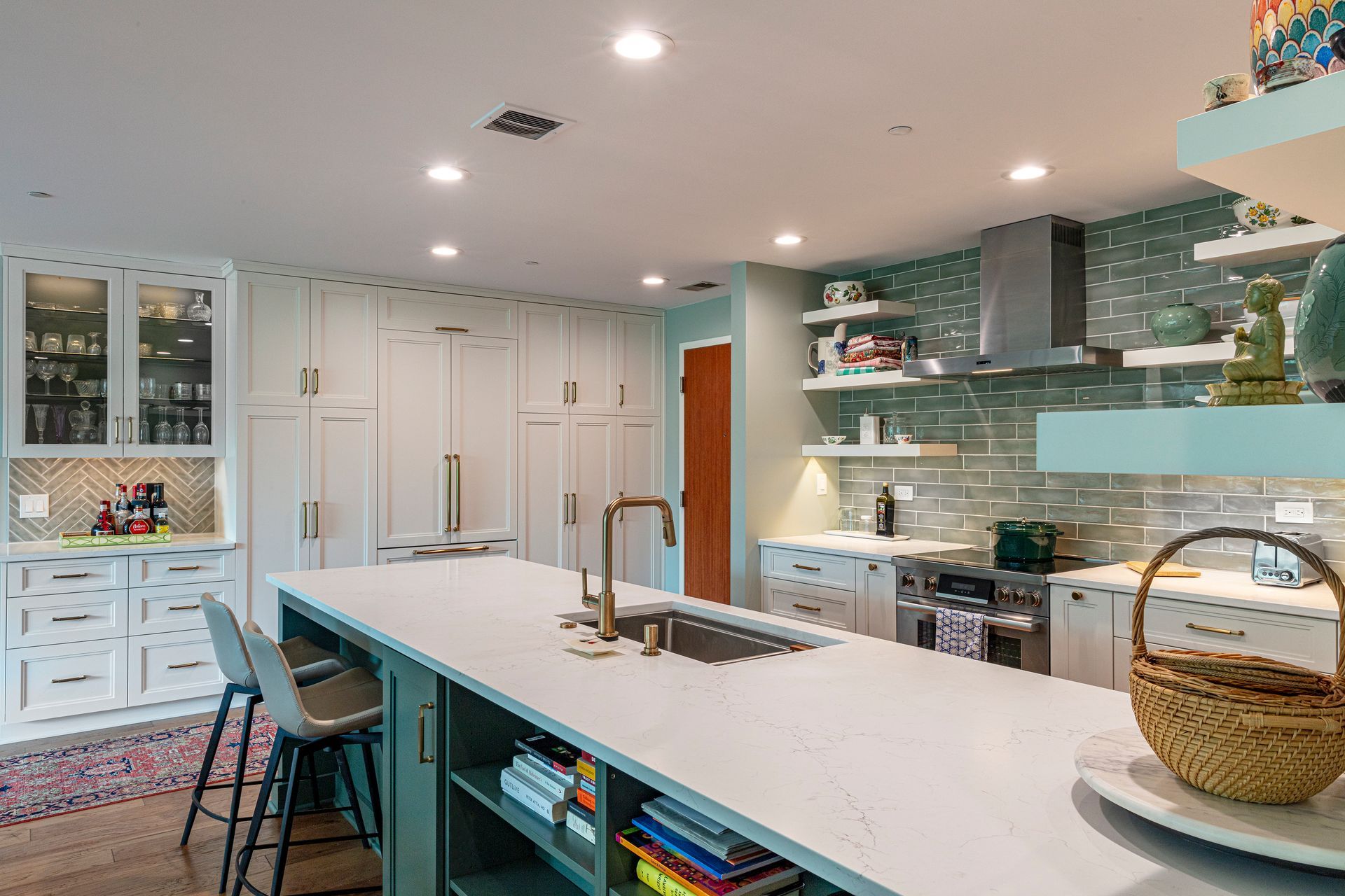 Bright modern kitchen with white island, teal accents, pendant lights, and glass backsplash