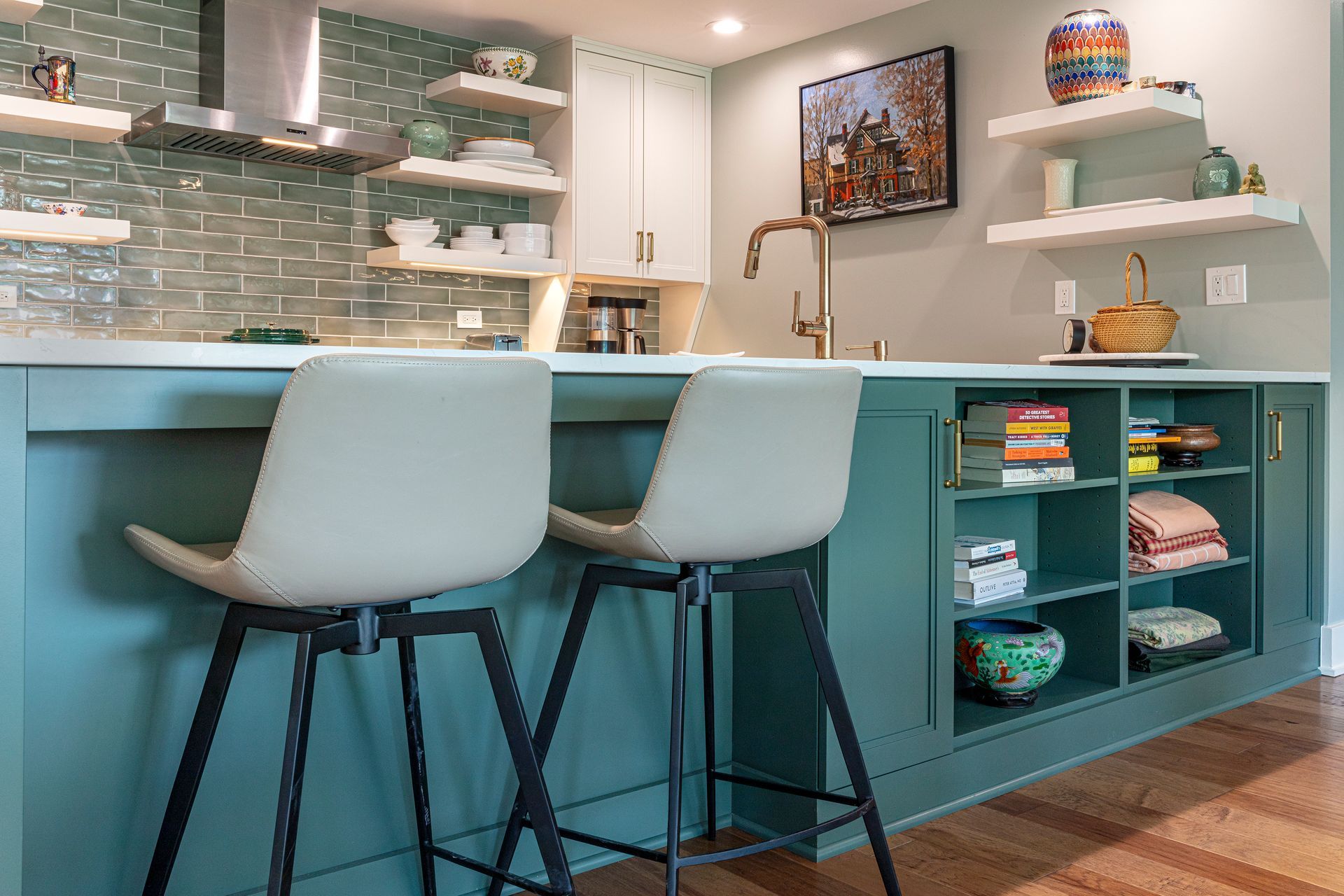 Modern kitchen with teal island, two white stools, open shelves, and a tiled backsplash.
