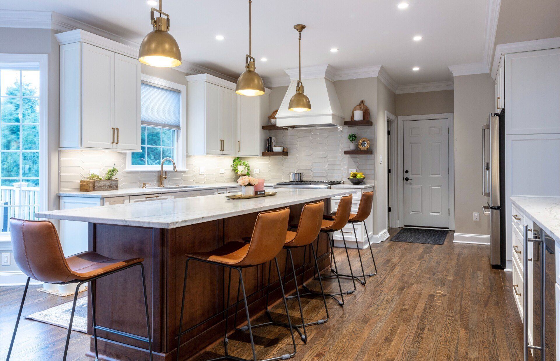 Bright modern kitchen with white cabinets, wood island, pendant lights, and bar stools