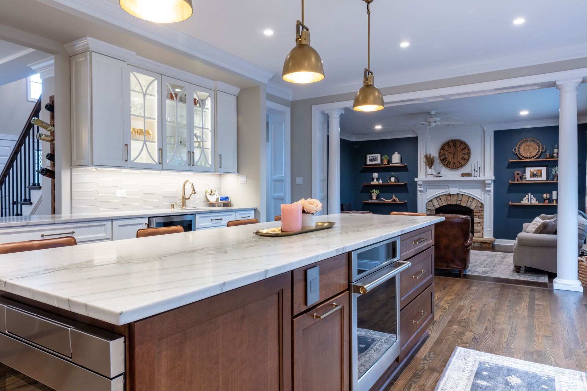 Modern kitchen with large island, white cabinets, pendant lights, and built-in shelving in the background