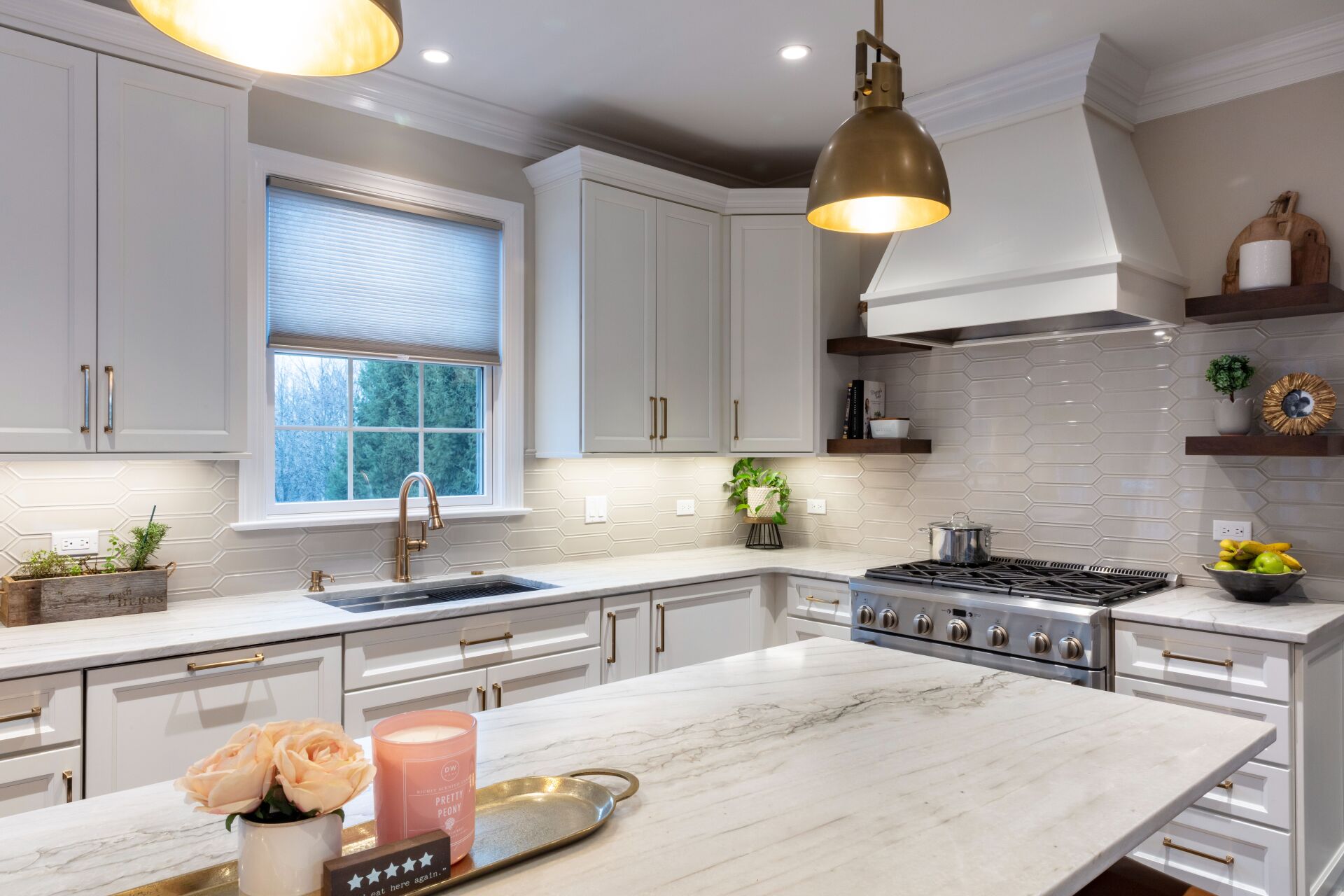 Bright modern kitchen with white cabinets, marble island, and brass pendant lights