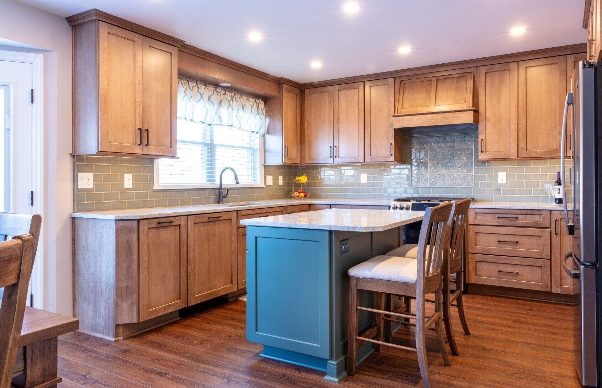 Bright kitchen with wood cabinets, stainless appliances, and a teal island in the center