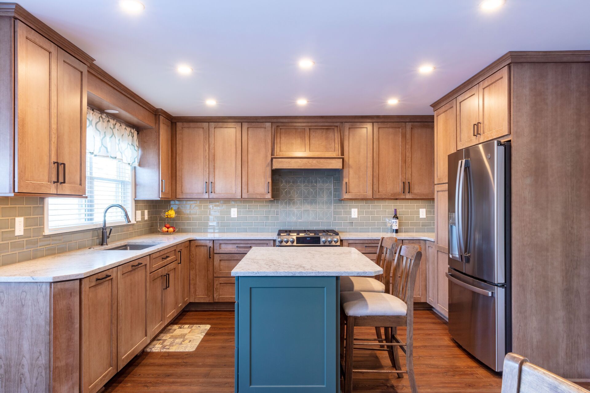 Bright kitchen with wooden cabinets, stainless appliances, and a blue island with two stools