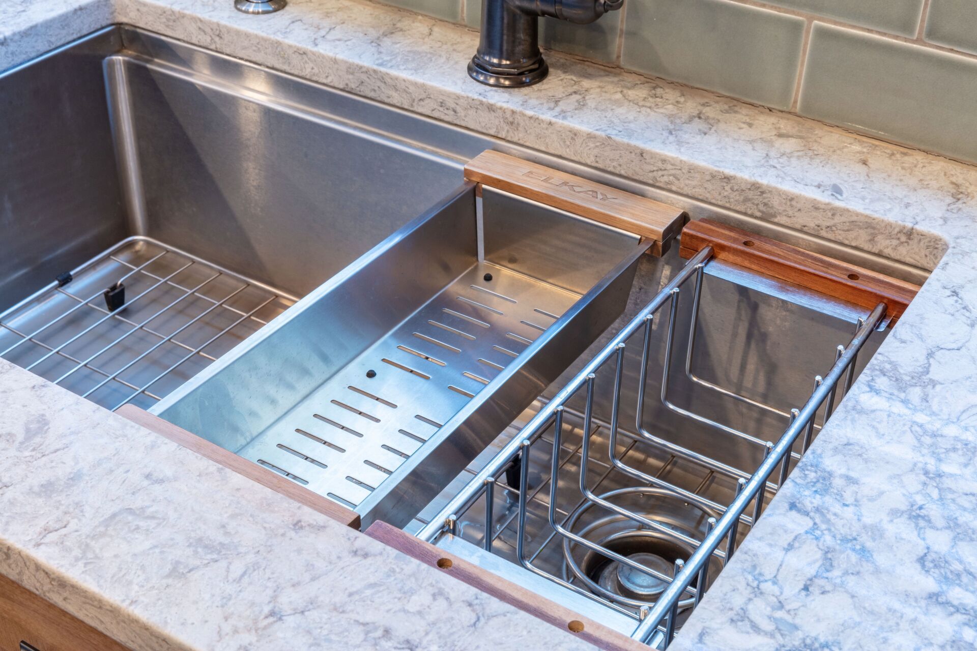 Stainless steel kitchen sink with built-in dish racks and drain compartments on a marble countertop