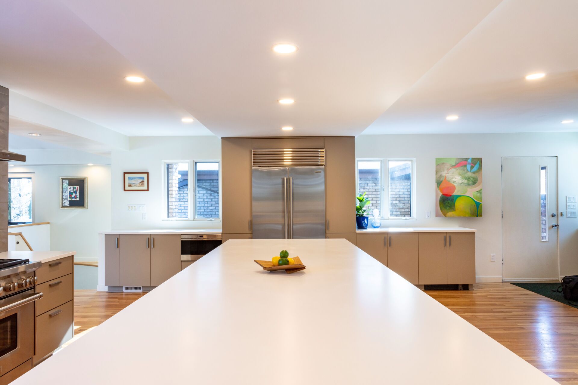 Modern kitchen with a large white island, stainless-steel appliances, and bright recessed lighting.