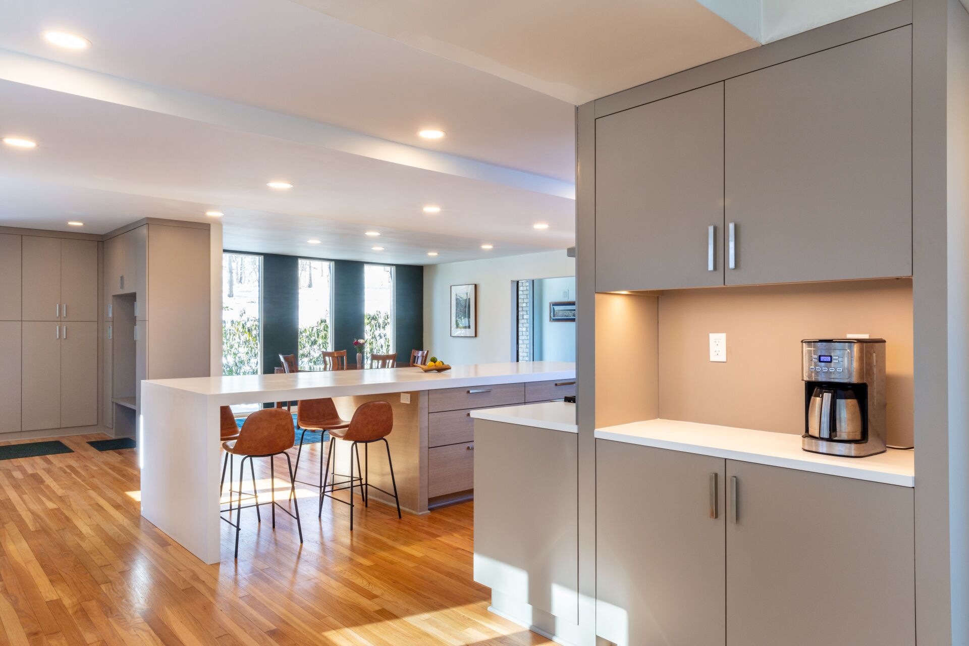 Bright modern kitchen with wood floors, island seating, and a coffee station built into gray cabinetry