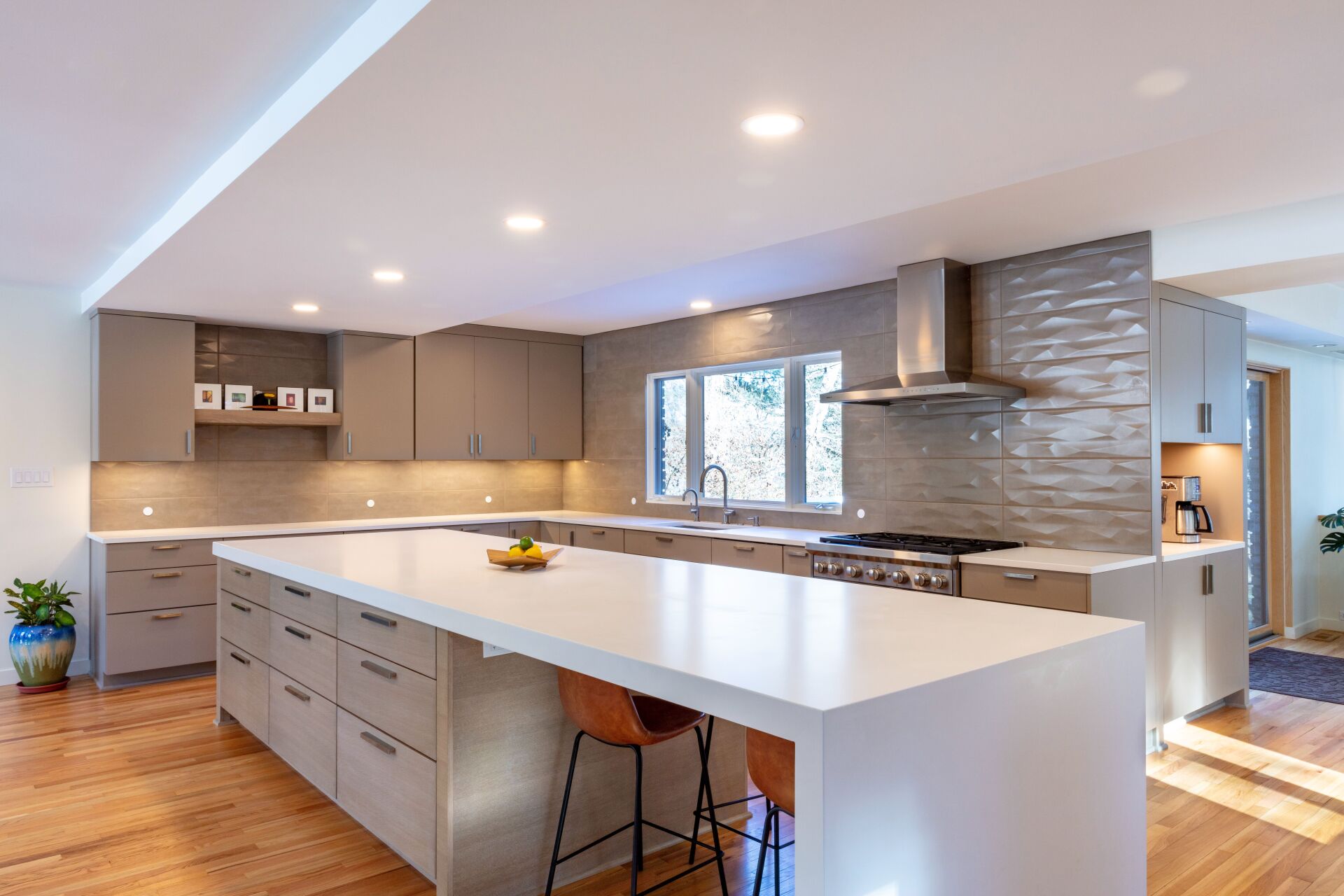 Modern kitchen with white island, gray cabinets, wood floor, and stainless steel appliances