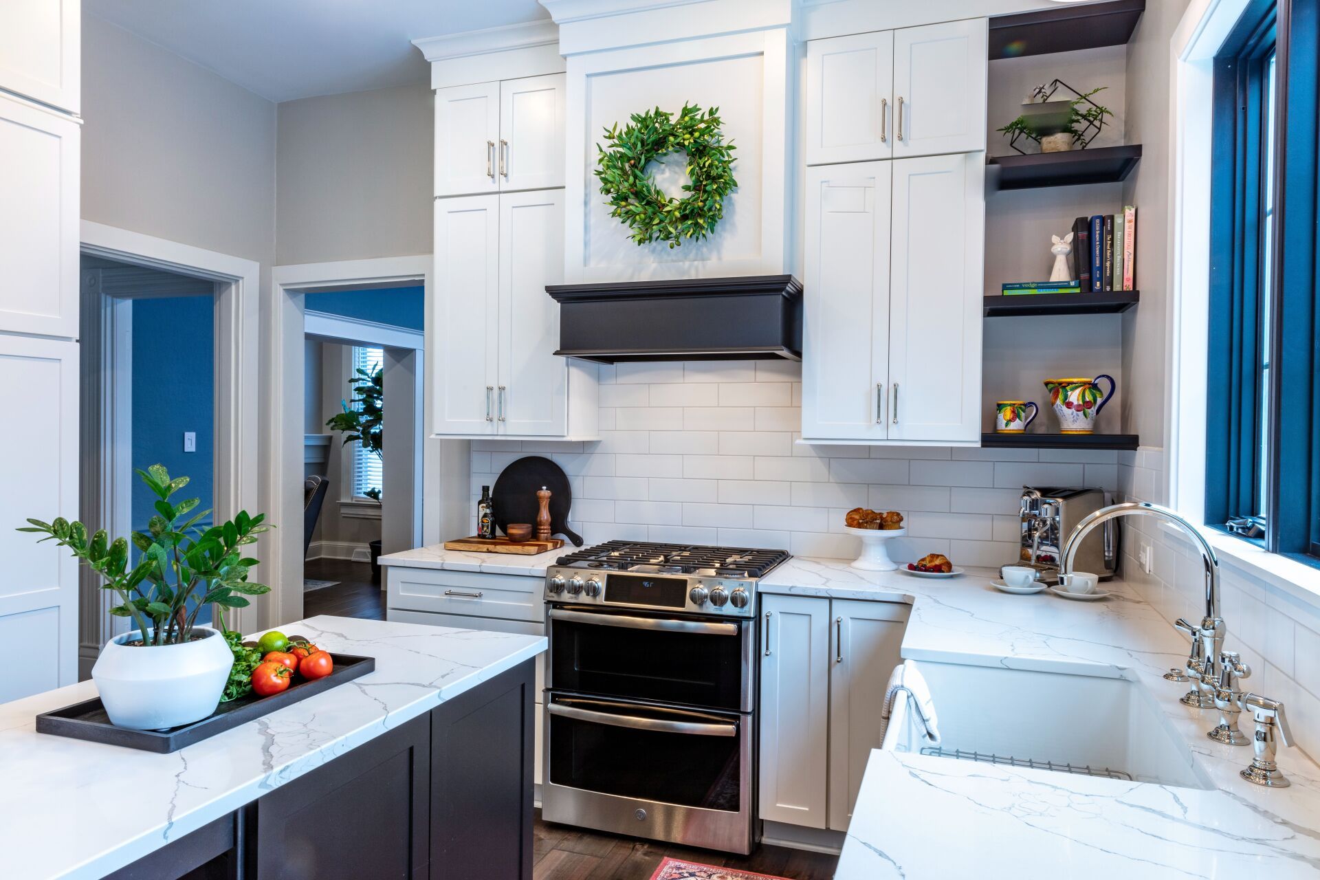 Bright white kitchen with stove, sink, plants, and wreath above the range.