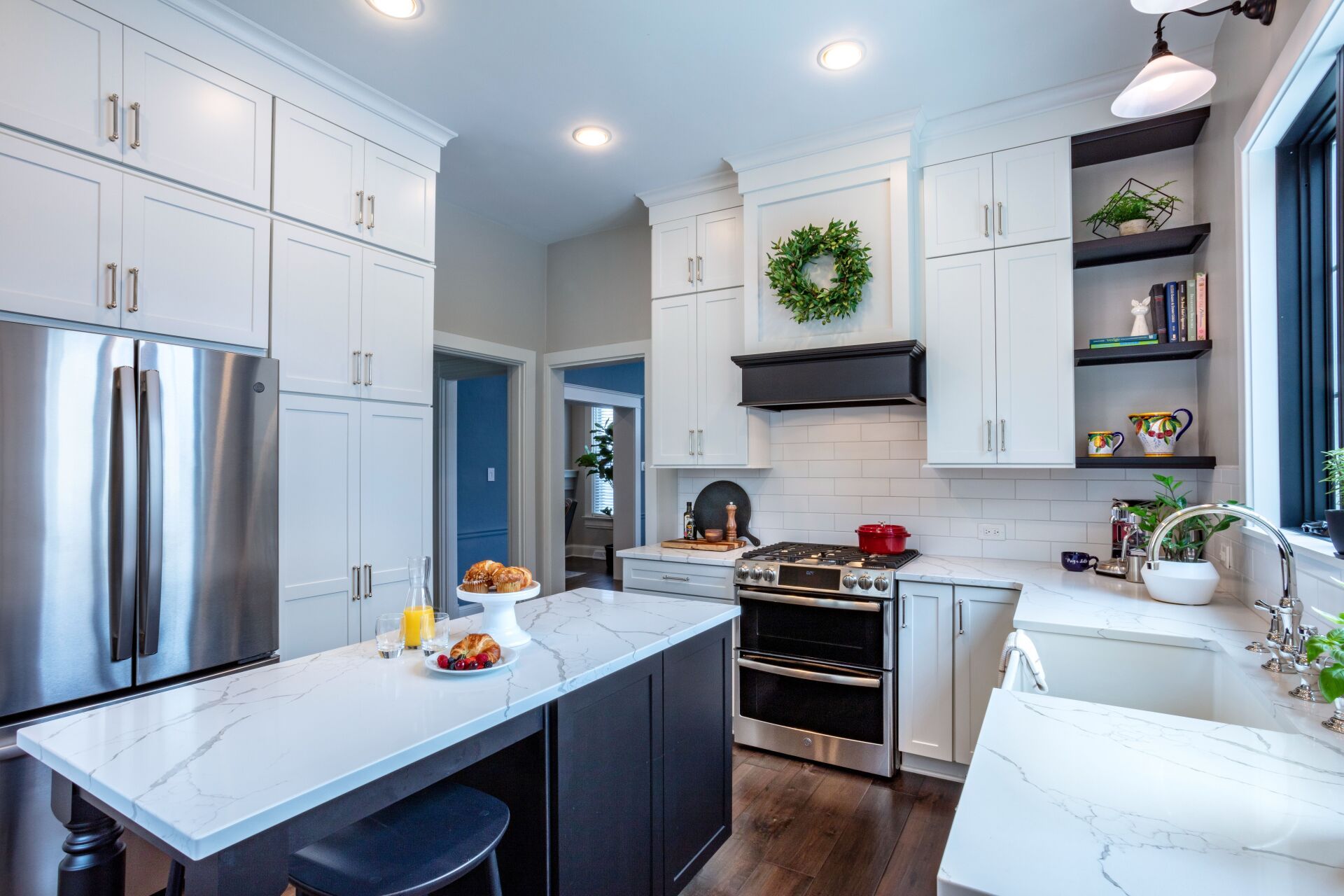 Bright white kitchen with stainless steel appliances, island, and wreath above the stove