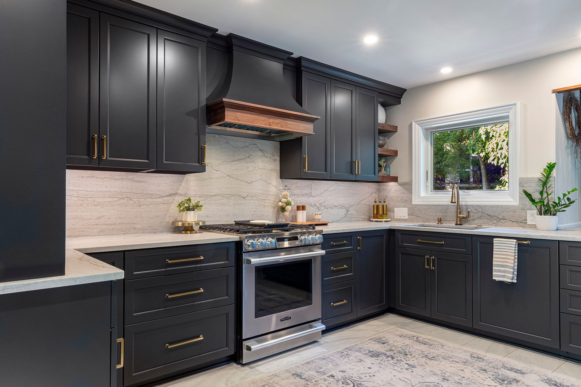 Modern kitchen with dark cabinets, stainless appliances, marble backsplash, and a window over the sink