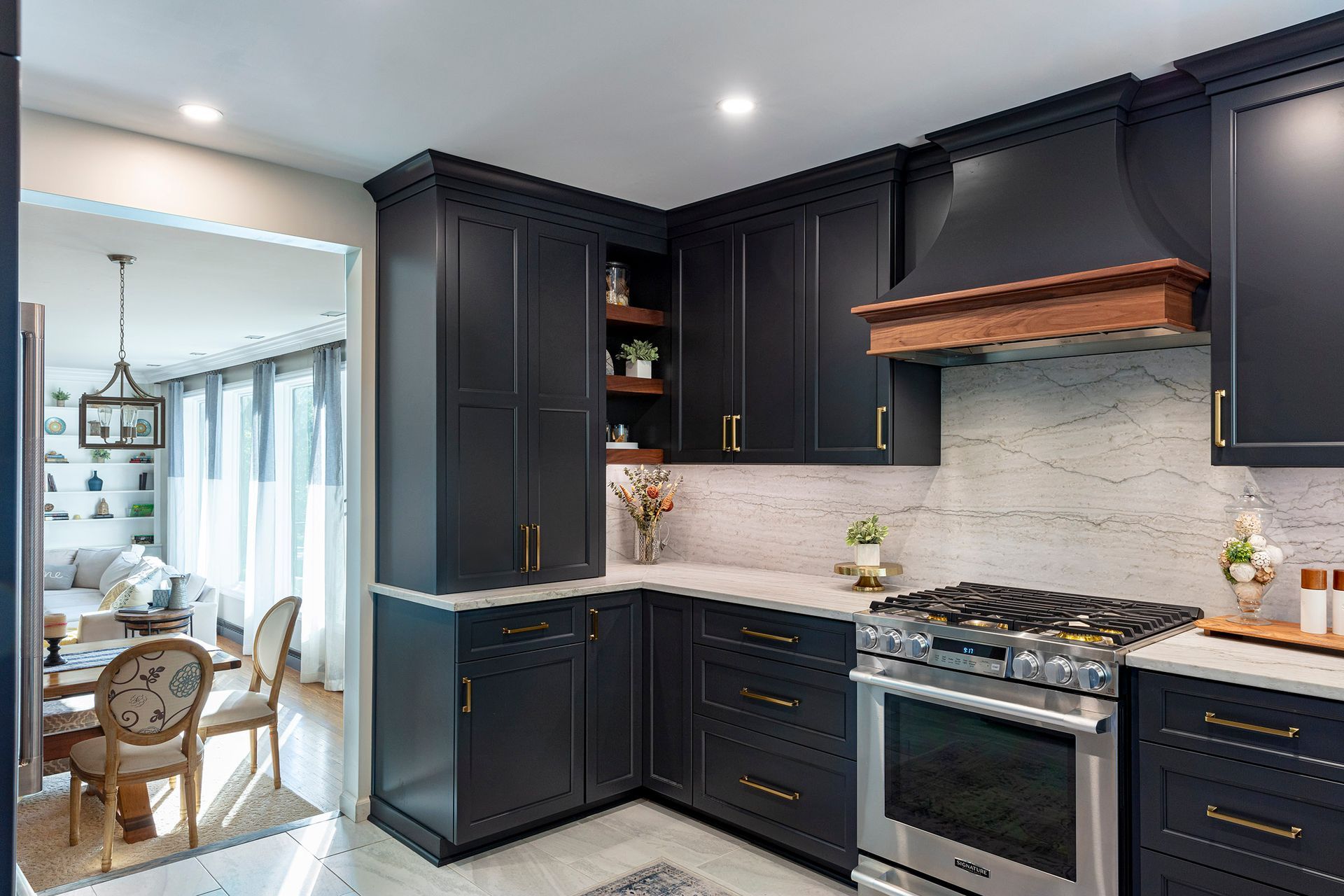 Modern kitchen with dark cabinets, stainless stove, white tile backsplash, and adjacent dining area