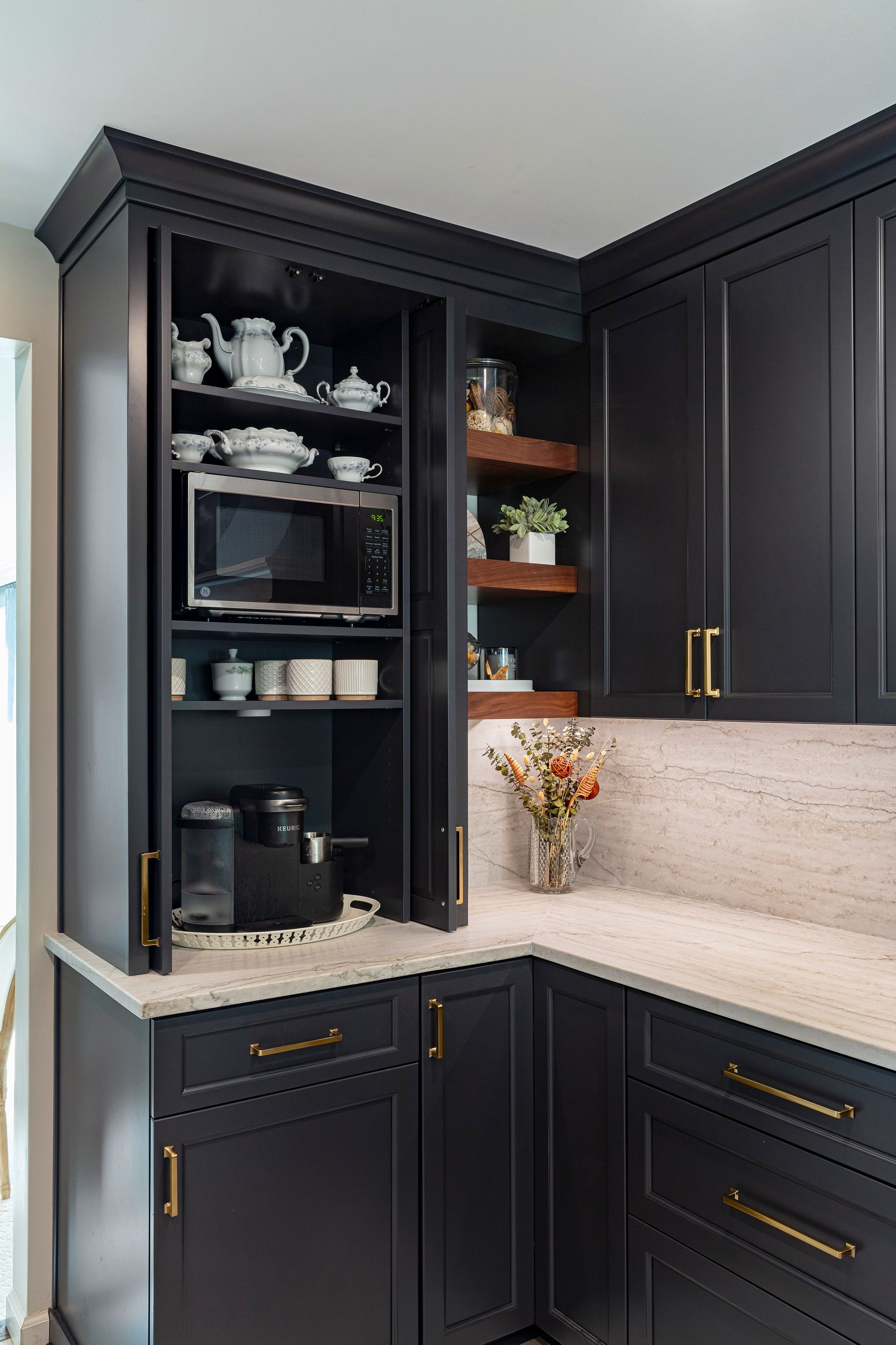 Black kitchen coffee station with open cabinet, espresso machine, mugs, and white countertops