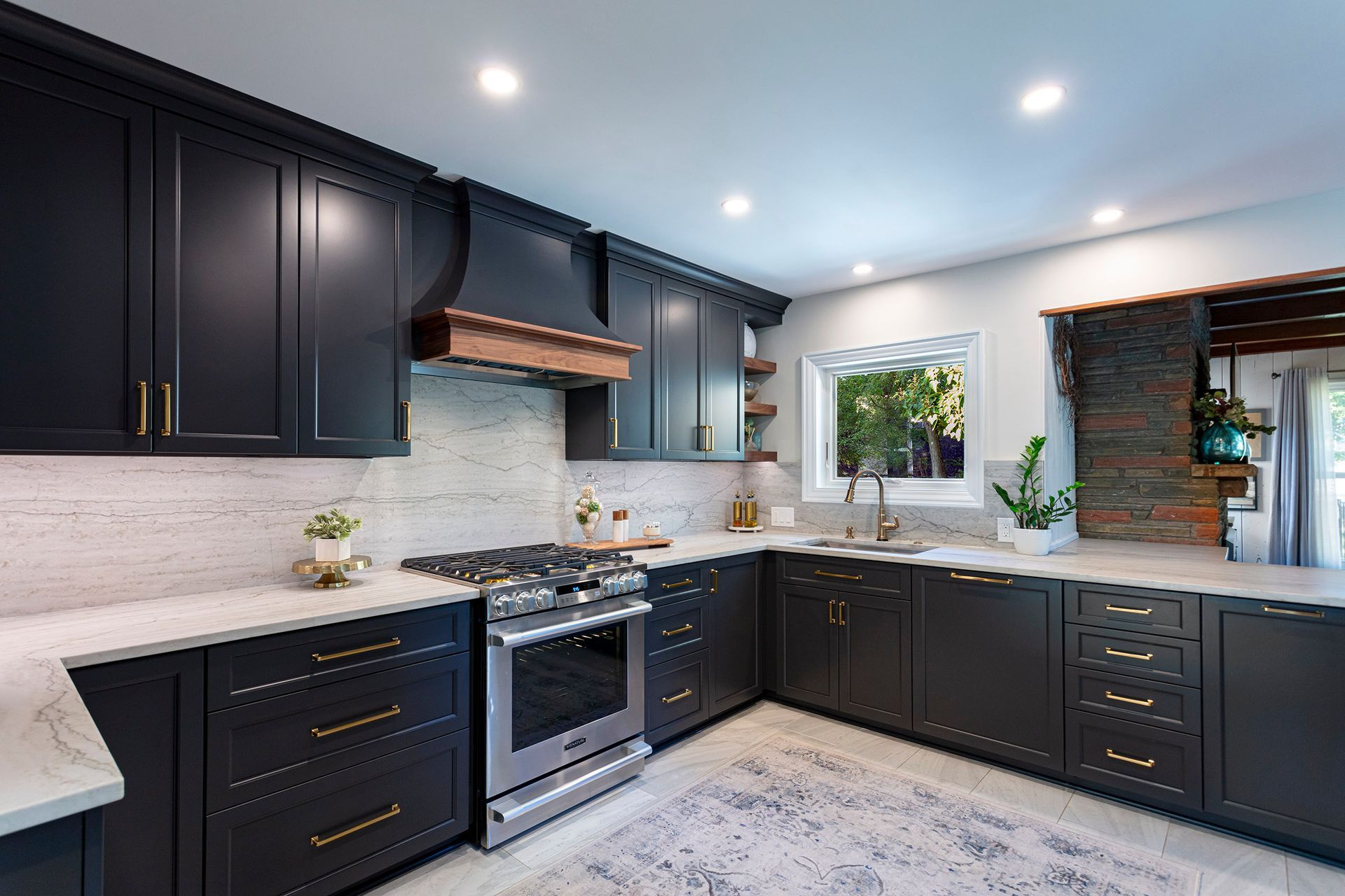 Modern kitchen with dark cabinets, white countertops, stainless stove, and bright recessed lighting