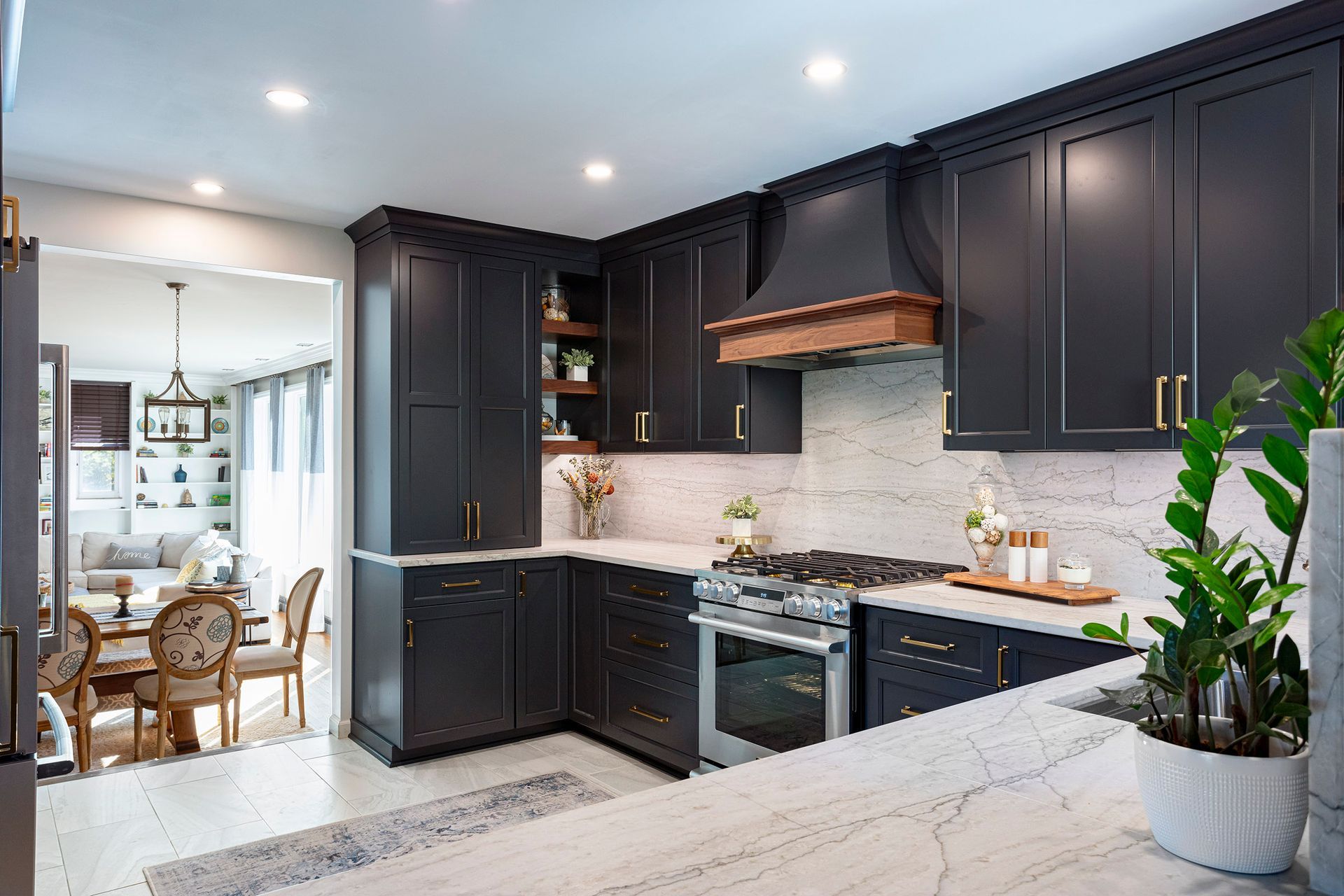 Modern kitchen with dark cabinets, white countertops, stainless stove, and a dining area in the background