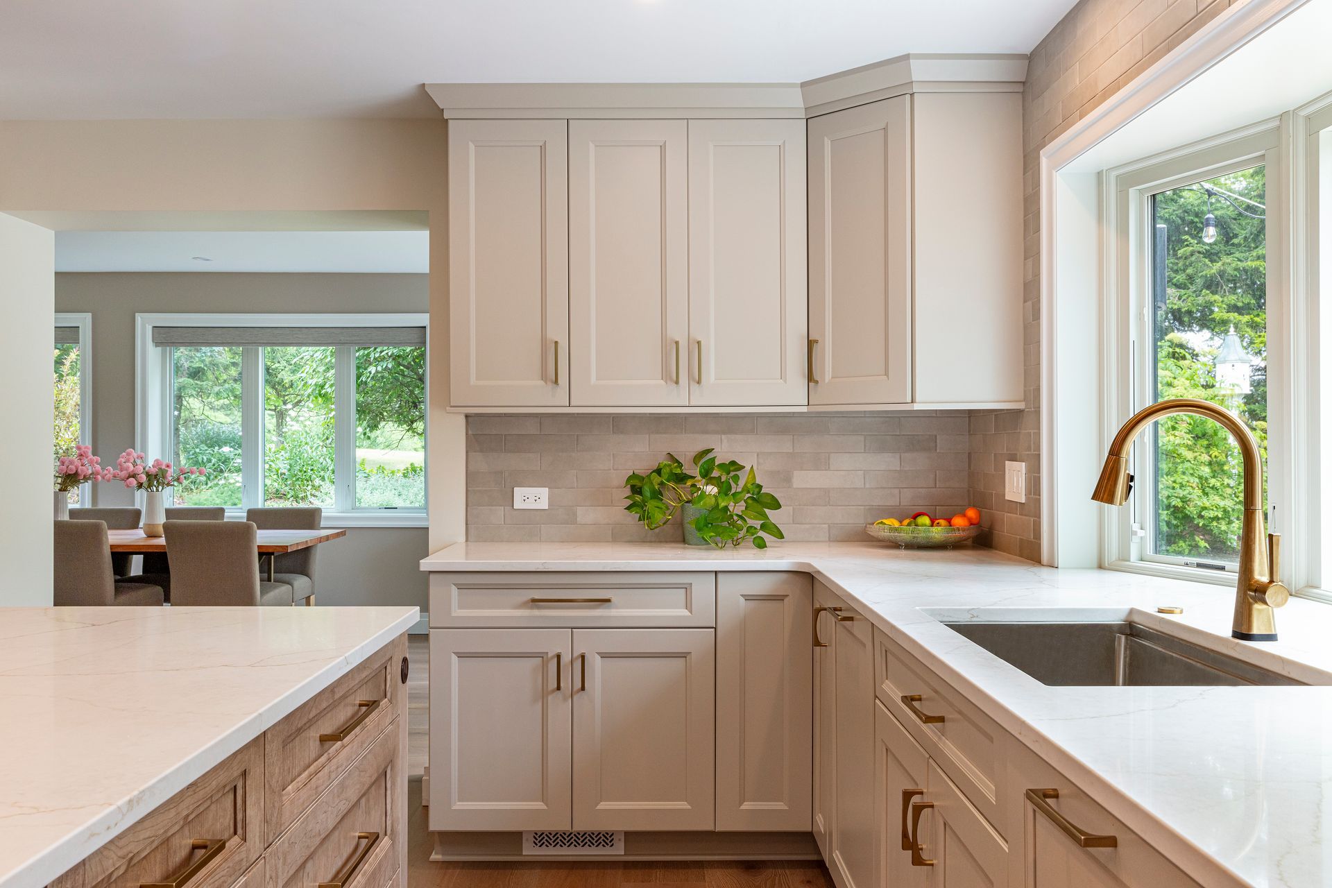 Bright modern kitchen with white cabinets, light countertops, and a window over the sink
