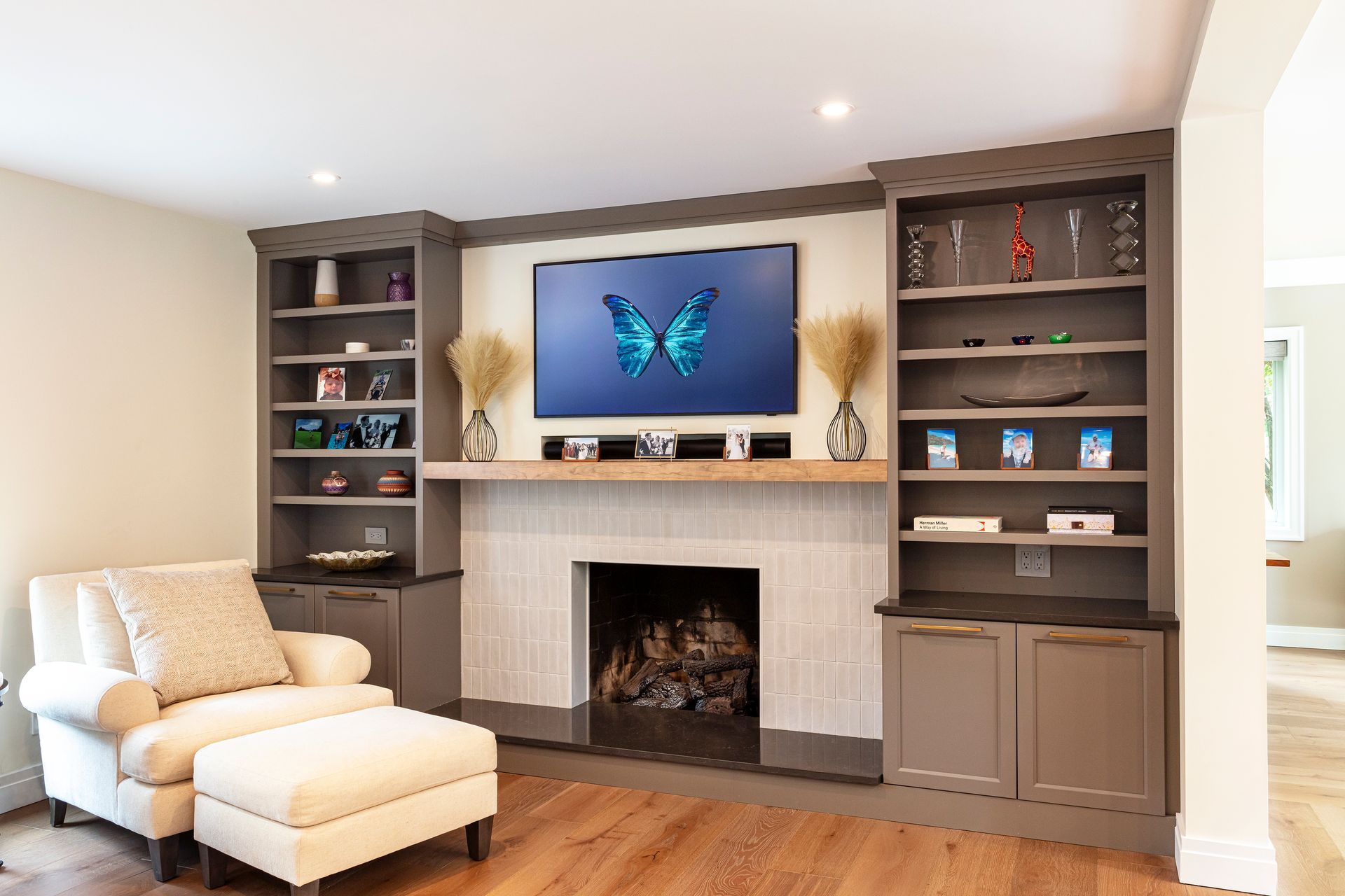 Modern living room with fireplace, built-in shelves, white chair, and TV displaying a butterfly.