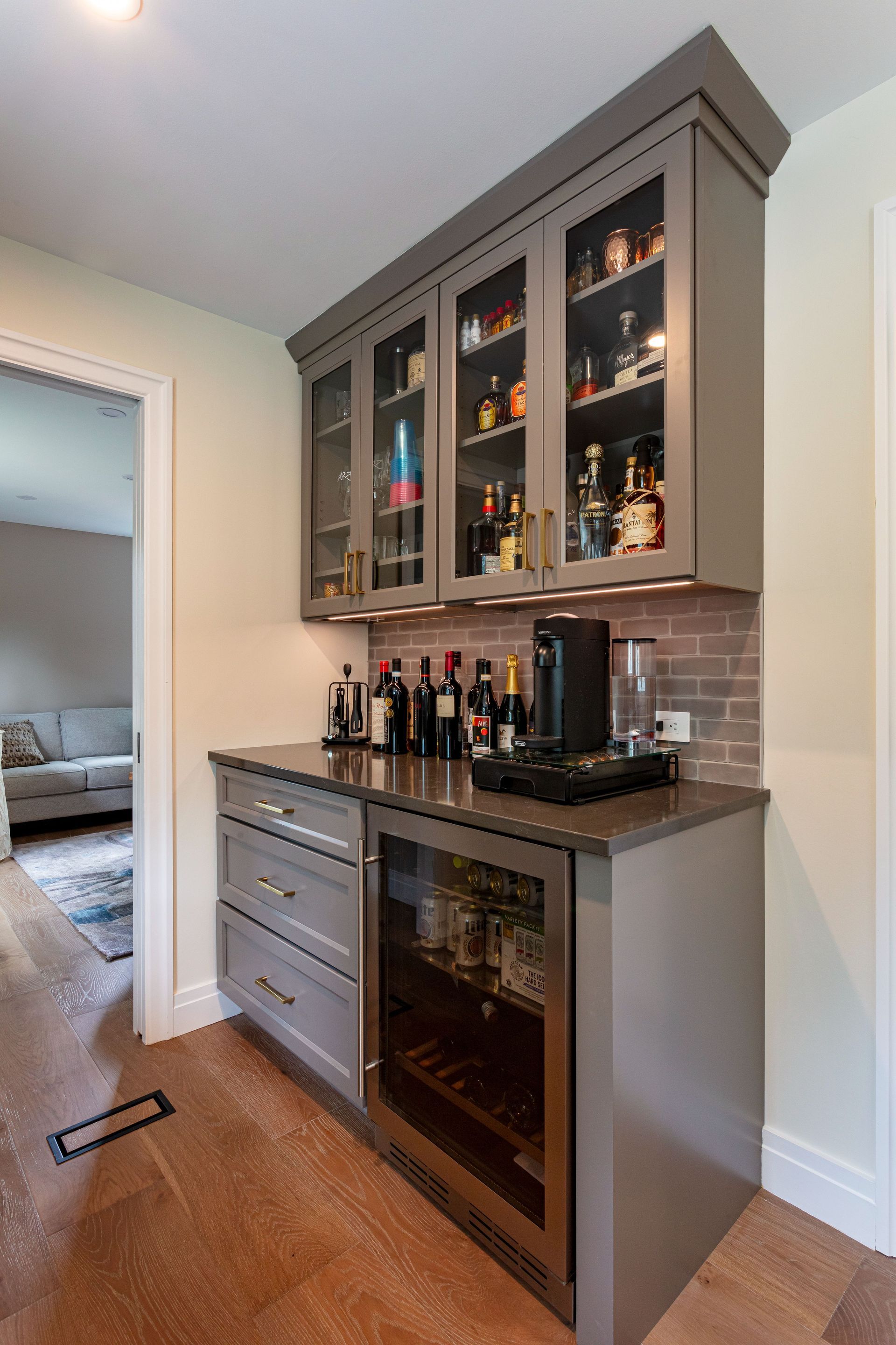 Built-in bar cabinet with glass doors, wine bottles, and granite countertop in a home hallway