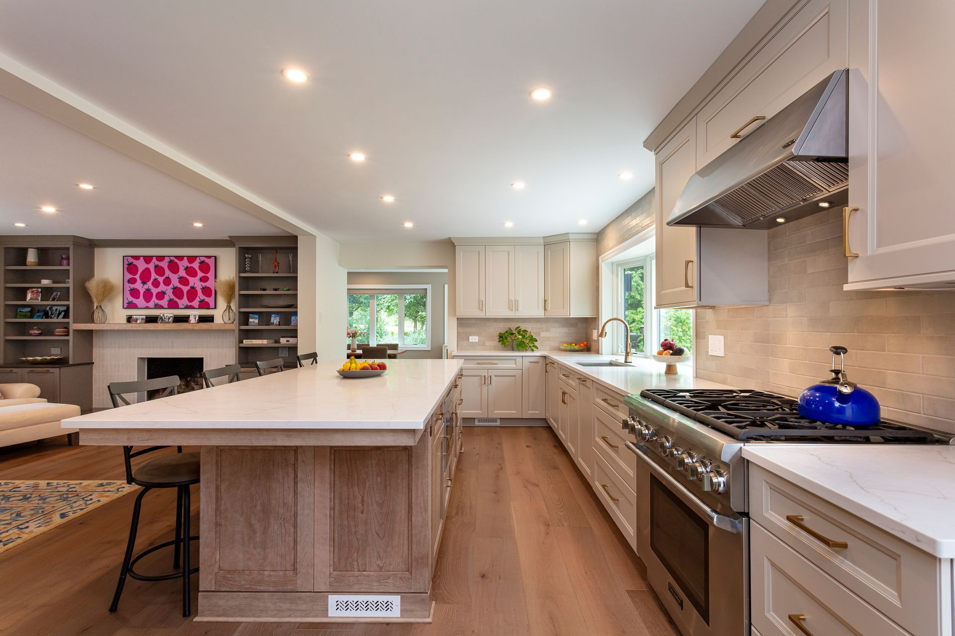 Modern white kitchen with a large island, stainless range, and light wood floors