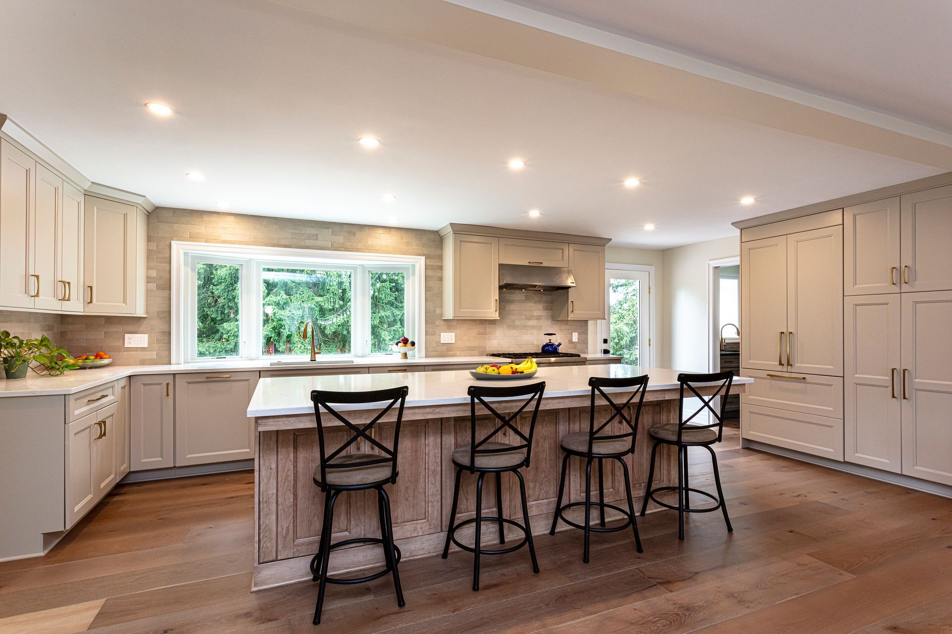 Bright modern kitchen with white cabinets, large island, bar stools, and a window over the sink