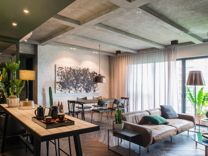 Modern open-plan living room with gray sofa, dining area, and large windows with sheer curtains