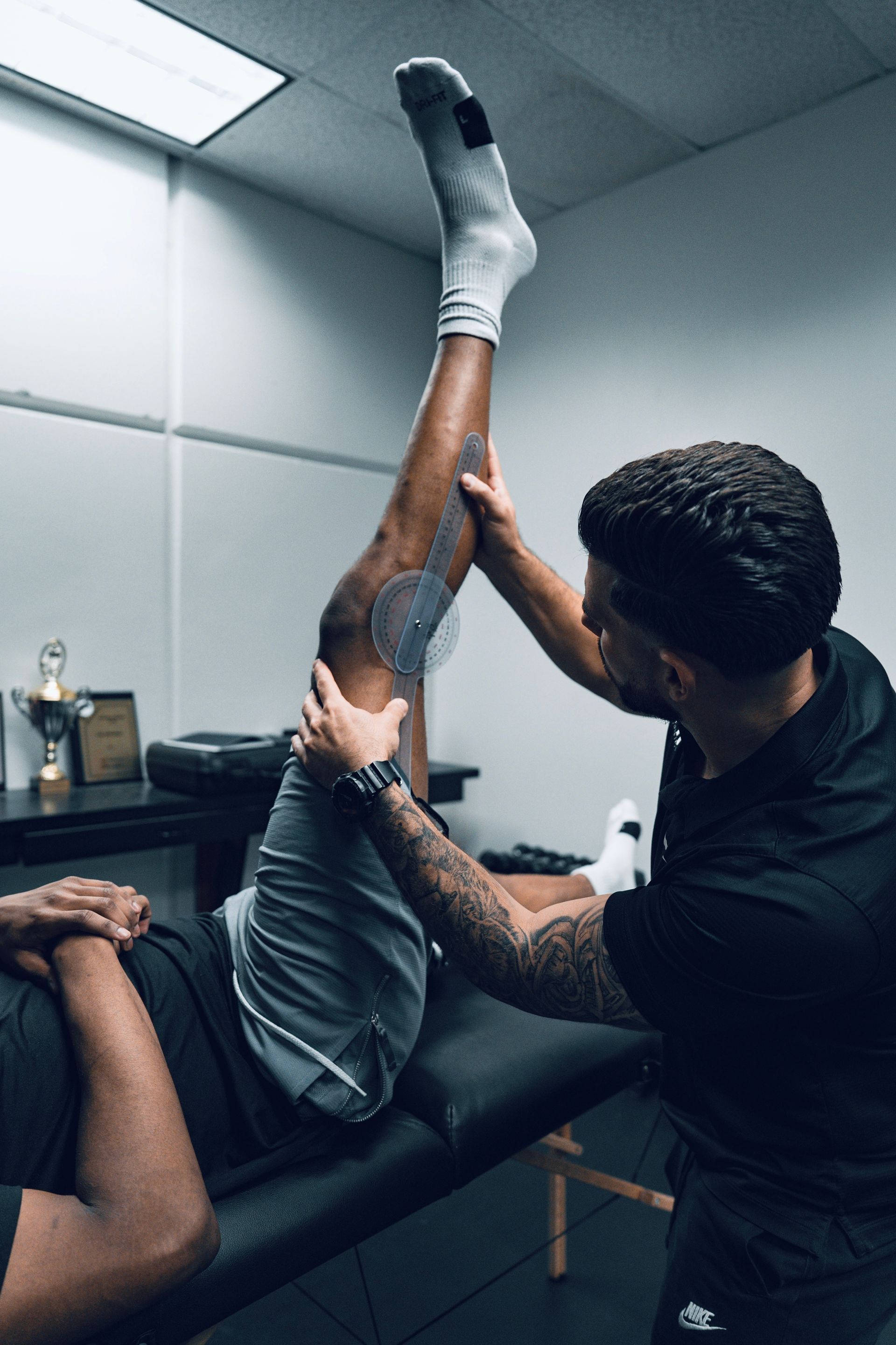 A man is stretching another man 's leg on a table.