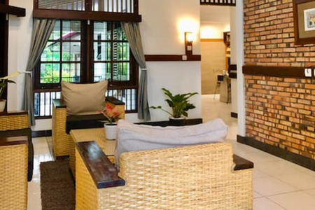Living room with wicker furniture, a brick wall, and a window with green view.