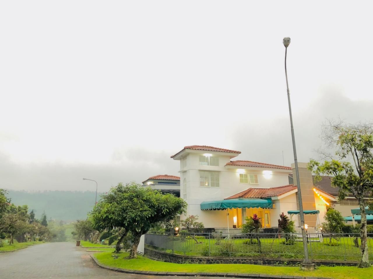 White two-story building with a tower, green awnings, and a street light on a cloudy day.