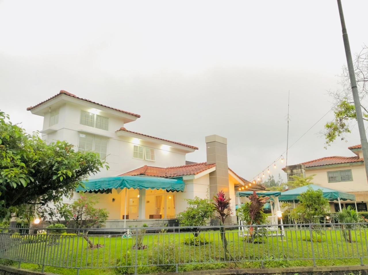 White house with red tile roof, covered patio with green awning, and green lawn in front.