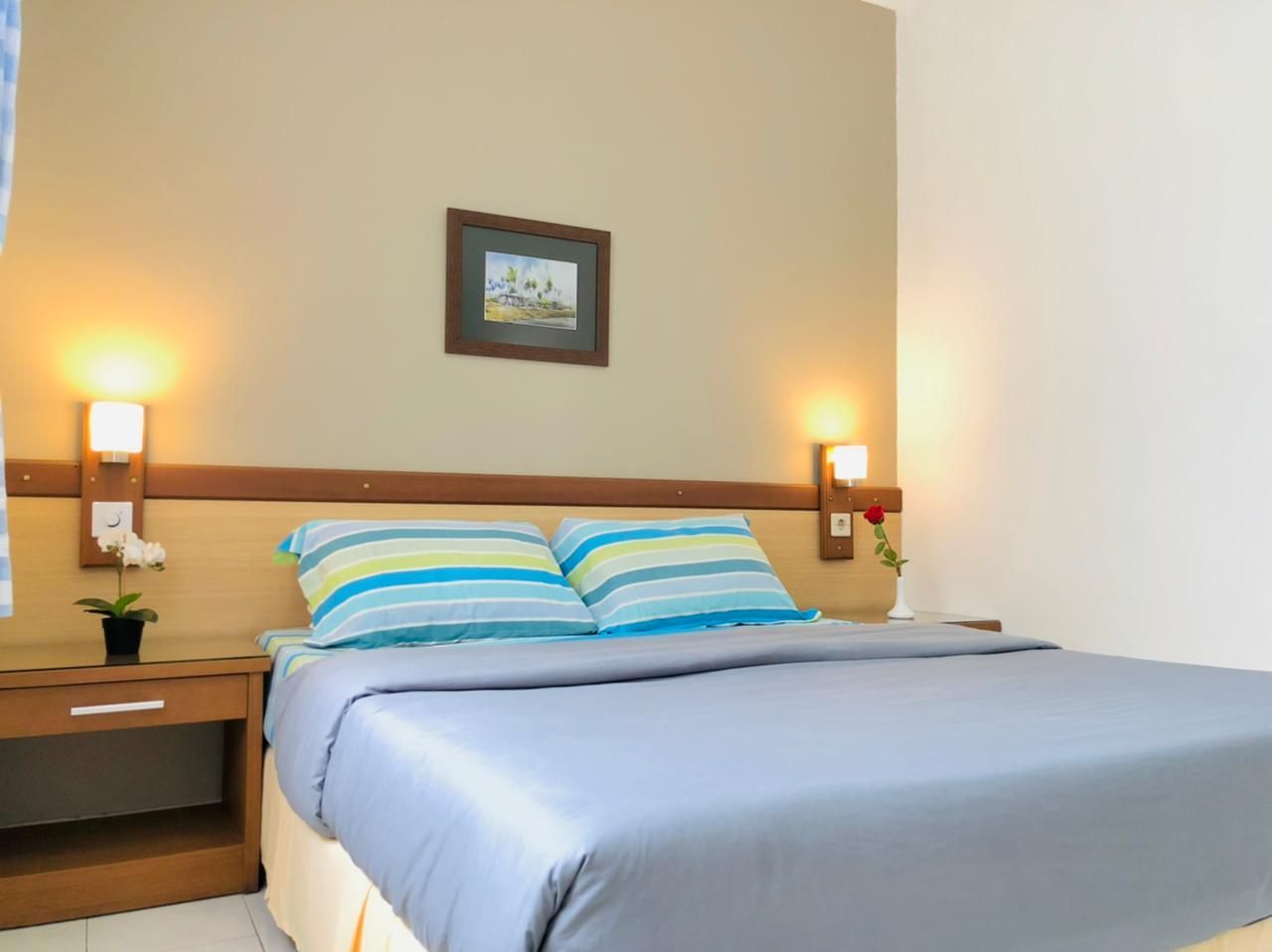 Bedroom with bed, nightstands, lamps, and a small framed picture.