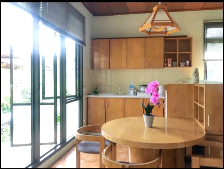 Kitchen with wooden cabinets, round table, and large windows. Pink orchid on table.