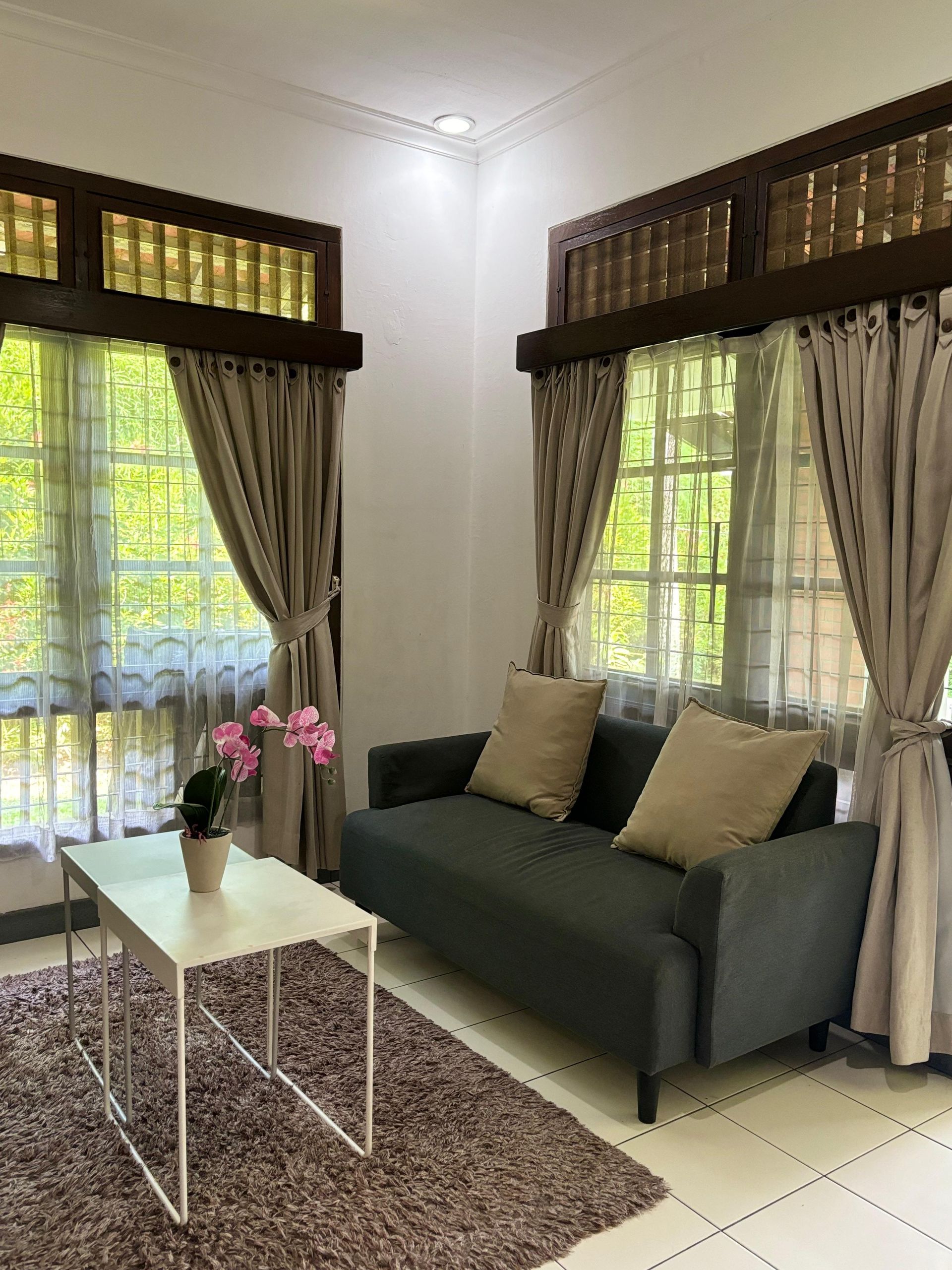 Living room with gray sofa, white coffee table, and windows with beige curtains.