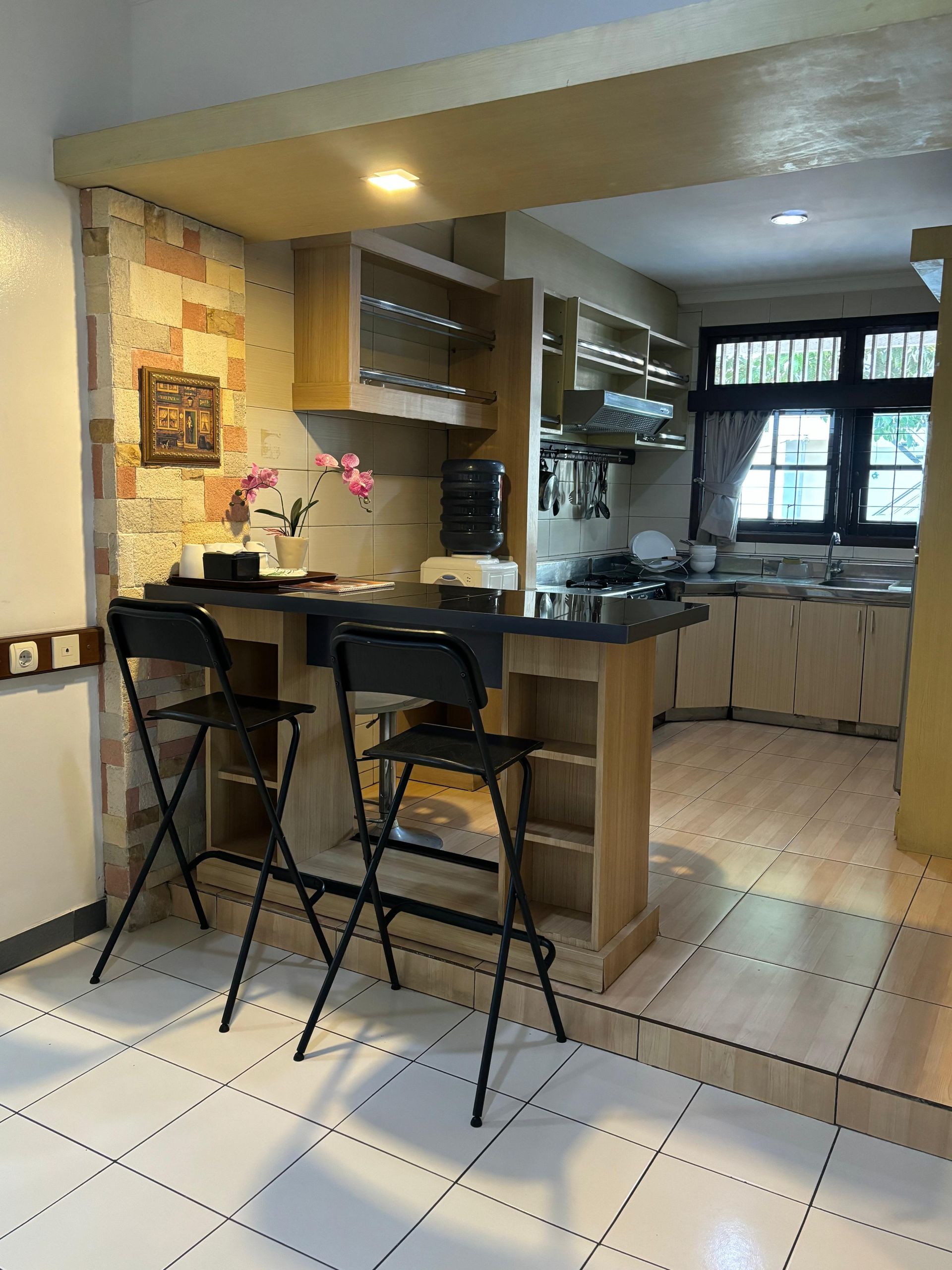 Kitchen with a breakfast bar, two black stools, and light-colored cabinetry.