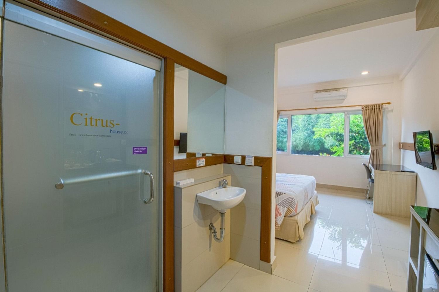 Hotel room with a shower, sink, and a view of a bed and window.
