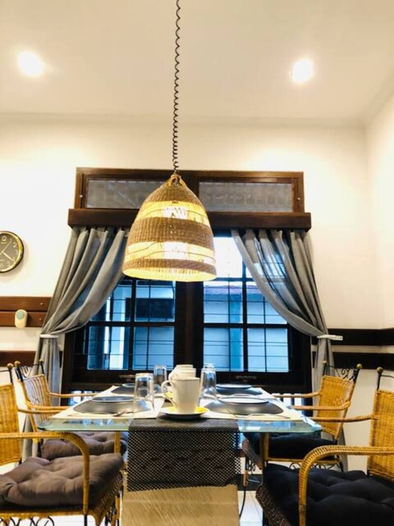 Dining room: Woven pendant lamp over a table set for a meal near a window with curtains.