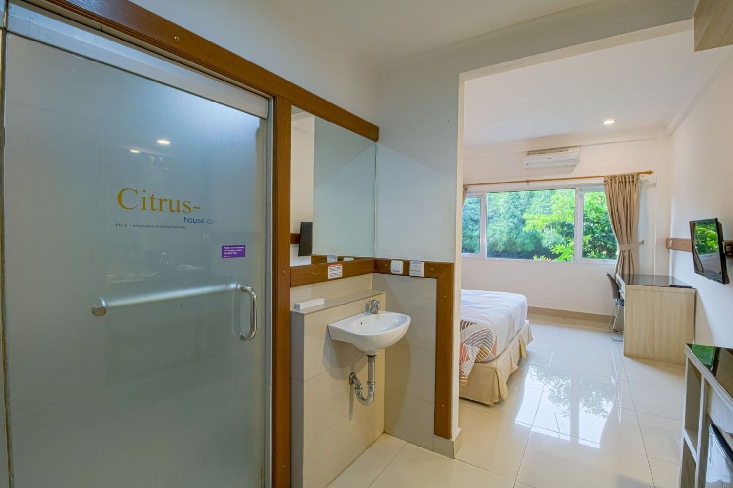 Hotel room interior with a frosted glass shower door and bed visible.