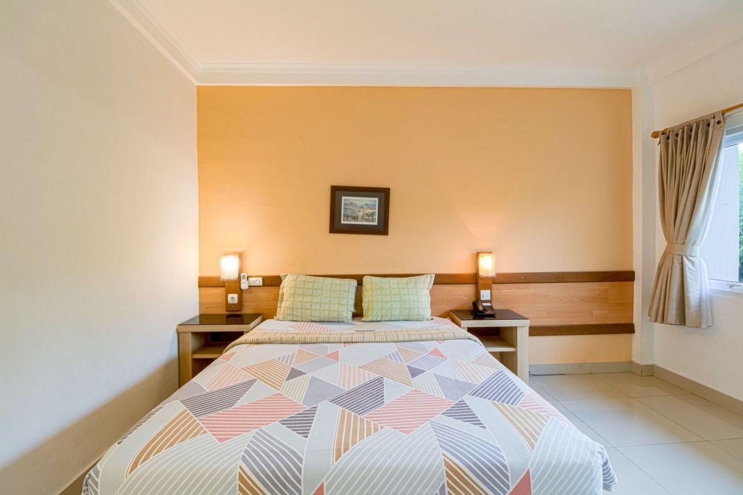 Bedroom with a bed, nightstands, lamps, and a window with curtains. Walls are tan.