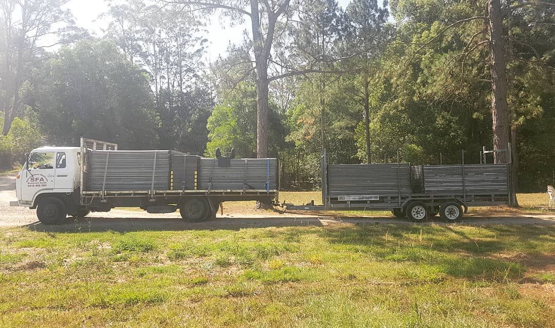 White Truck With a Trailer Attached to It is Parked in a Grassy Field — Safety Fence Australia in Mullumbimby, NSW