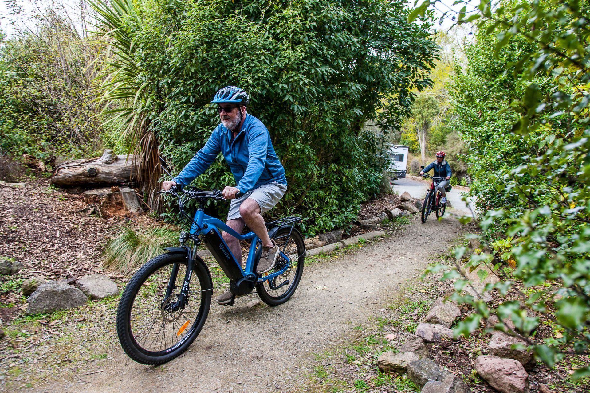 Couple Riding eBikes in forest with Motorhome Couple Riding eBikes in forest with Motorhome