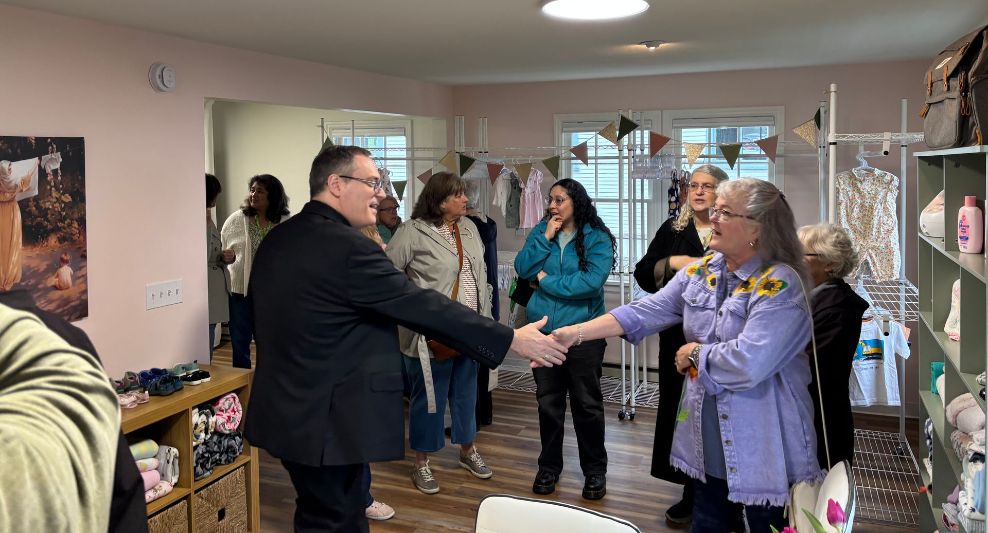 People chatting and shaking hands in a small room during an indoor gathering