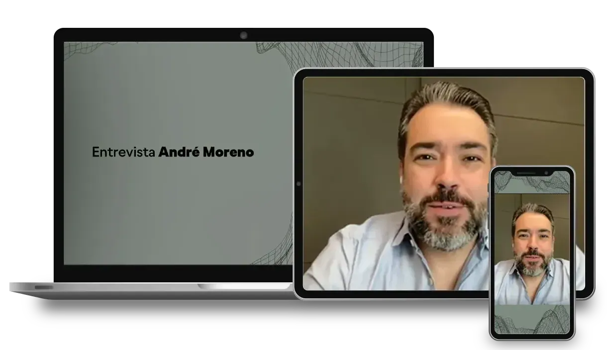 Um homem com barba está sentado em frente a um laptop, tablet e celular.