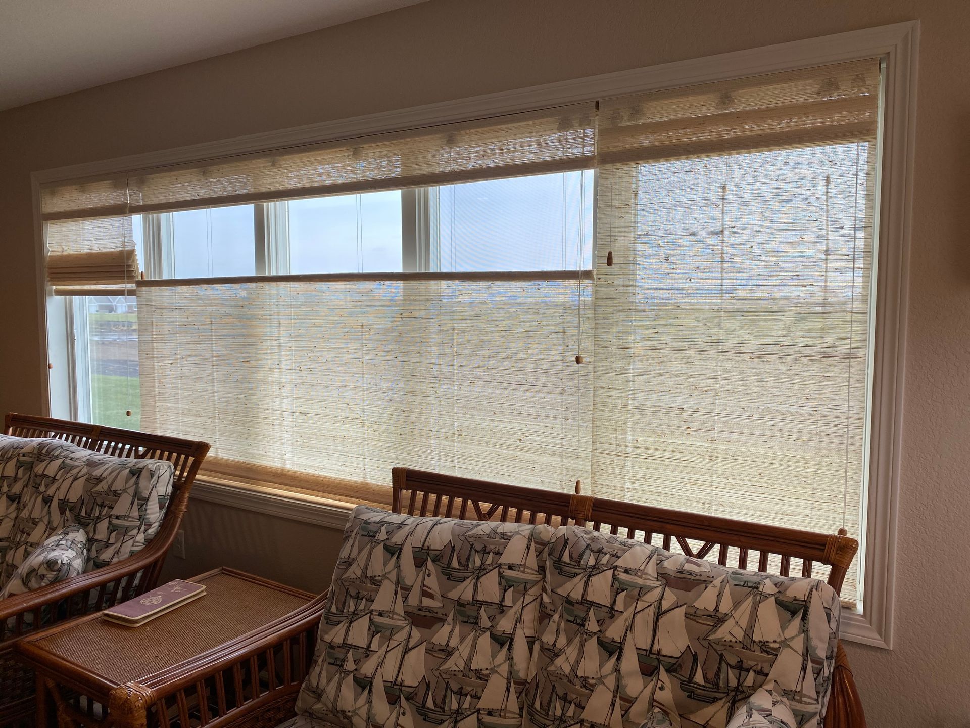 Woven blinds cover a window in a room with nautical-print furniture.