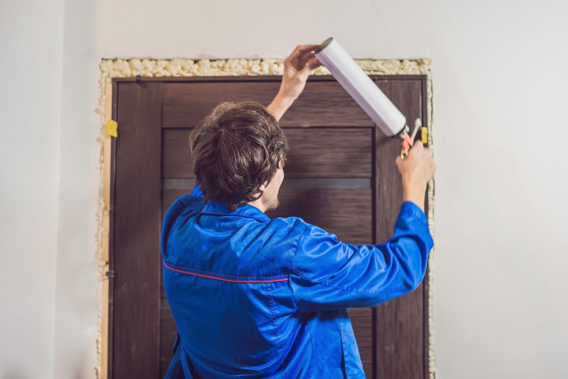 A handyman installing a door with mounting foam in a room
