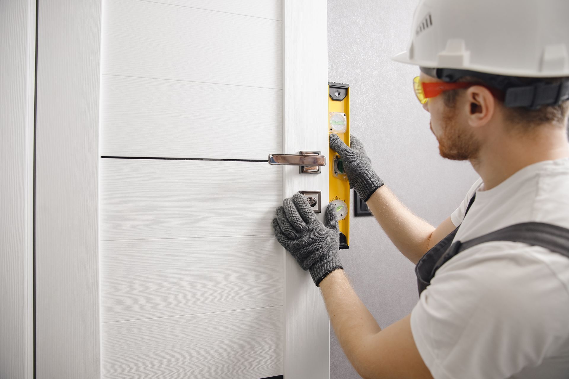 Worker leveling a white door.