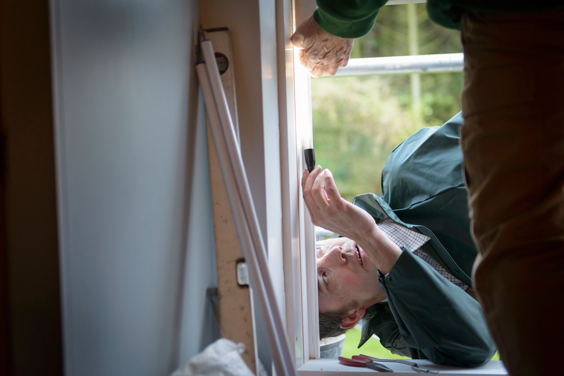 Two contractors adjusting new window in house, showcasing excellent window installation. Men installing a window