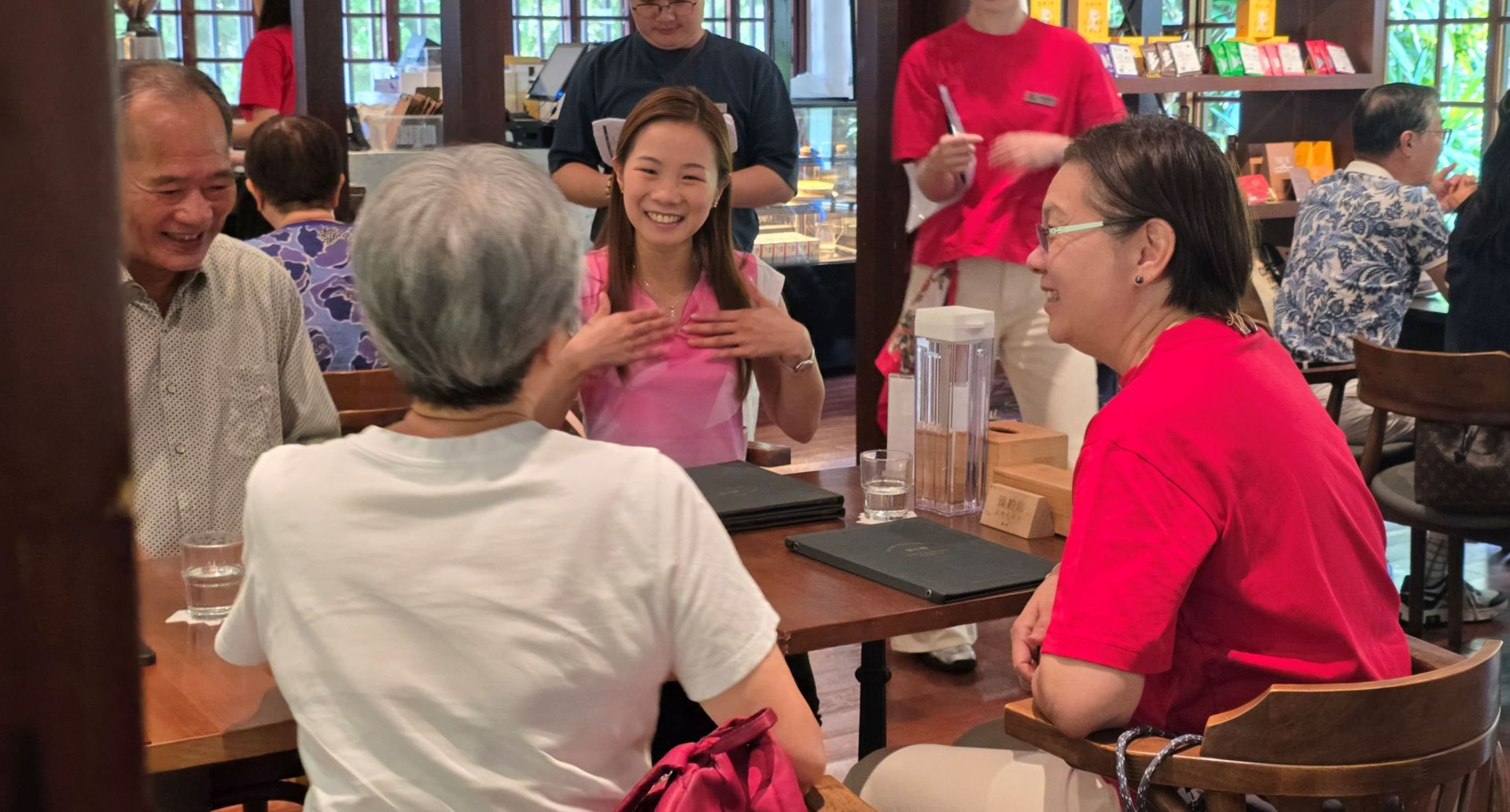 餐廳裡,人們圍坐在餐桌旁,面帶微笑,交談甚歡。餐廳內部環境優美,擺放著木質家具,還有其他顧客。