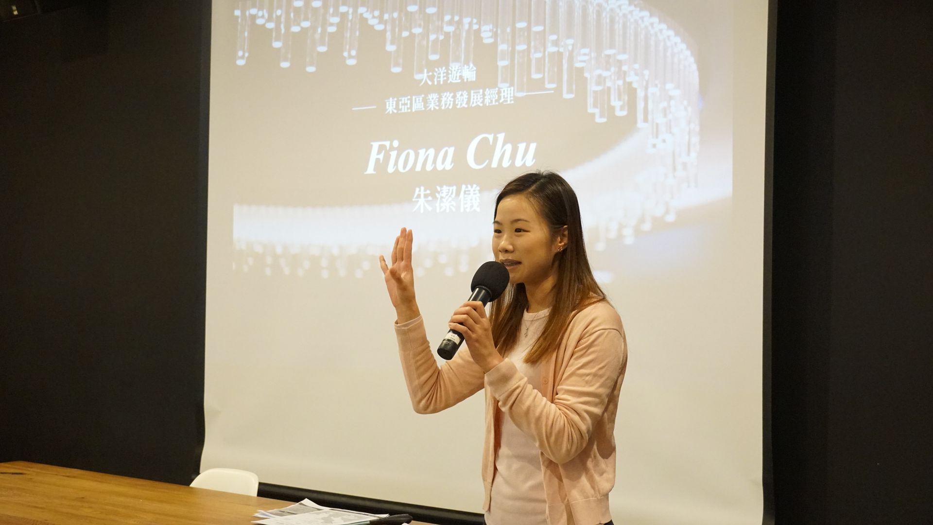 一間光線昏暗的房間，裡面有投影螢幕、桌椅和餐桌椅。