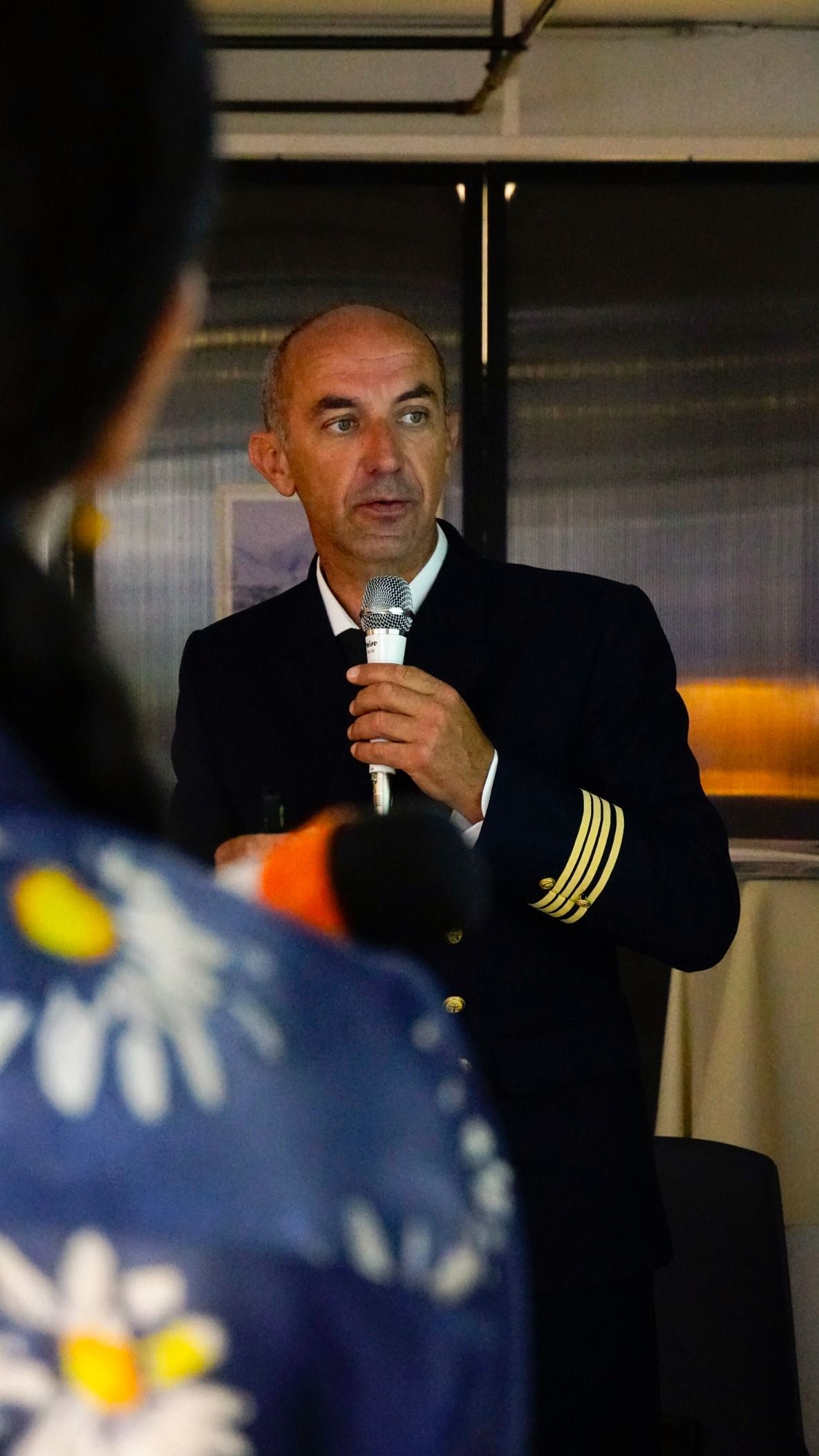 一名身穿海軍制服、袖子上有金色條紋的男子對著麥克風講話。