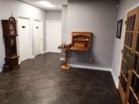 Empty hallway with dark flooring, white doors, and a wooden wall-mounted shelf/display
