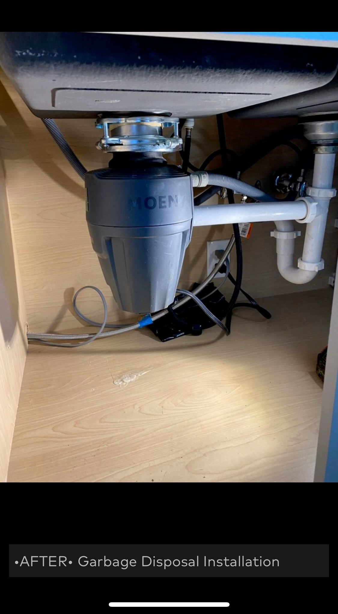 Garbage disposal installed under a kitchen sink. Grey and white plumbing visible.